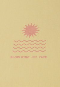 Žluté bavlněné tričko s růžovým grafickým motivem slunce nad vlnitými čarami a textem "SLOW RIDE" a "HIGH TIDE" v tučných kontrastních barvách.