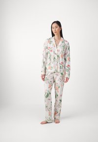 Floral pajama set featuring a white background, vibrant pink and green botanical print, button-up top, and straight-leg pants.