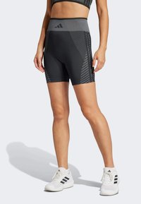 Pantaloni corti neri da atletica con una vita grigia a motivo e pannelli laterali testurizzati, realizzati in un tessuto elasticizzato per facilitare il movimento.