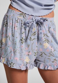 Lichtblauwe bloemen shorts van zachte stof, met een gerimpelde zoom, een elastische tailleband en een satijnen strik aan de voorkant.