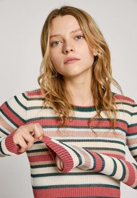 Geribbeld sweater met multicolore strepen in tinten van roze, groen en crème. Beschikt over lange mouwen met contrasterende kleuren en textuur van de manchetten.