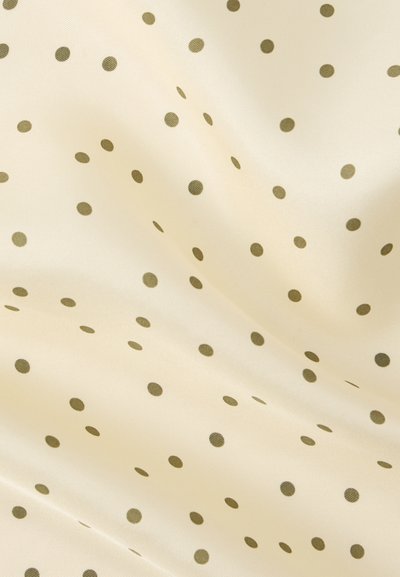 Ύφασμα κρεμ χρώματος με ομοιόμορφα διατεταγμένες μικρές καφέ πουά και απαλές πτυχώσεις που δημιουργούν απαλά σκιάσματα.