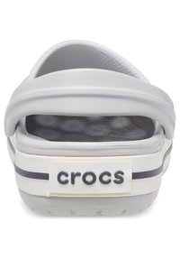 Sivi gumeni klompf sa stražnjim trakama, teksturiranom uloškom i bijelom trakom sa mornarsko plavom prugom i logom „crocs“. 