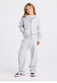 Gray zip-up hoodie with pockets, paired with matching sweatpants. Material is soft, with a relaxed fit. Sneakers have black and white accents.