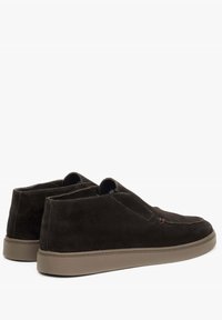 Ciemnobrunatne zamszowe buty wsuwane o gładkiej fakturze, zaokrąglonym nosku i jasnobrązowej gumowej podeszwie. Posiada minimalne detale przeszycia.