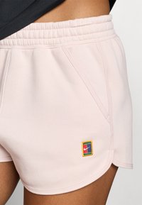 Pantalones cortos deportivos rosa, fabricados con una tela suave, que cuentan con una cinturilla elástica, bolsillos laterales y un logotipo de Nike bordado multicolor en el dobladillo.