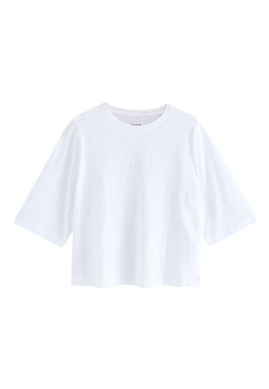 T-shirt blanc court en tissu doux, avec un col rond et des manches courtes larges à la coupe décontractée. Aucun motif ou accent visible.