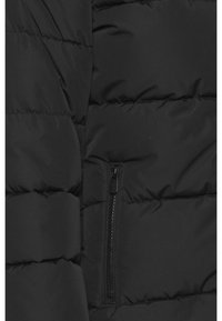 Section de veste matelassée noire avec des coutures horizontales et une poche fermée à fermeture éclair verticale visible.