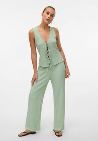 Ljusgrön tvådelad outfit med en ärmlös V-ringad topp med knytning och vida byxor med strukturerat mönster.
