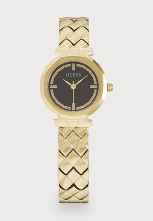 Montre dorée avec un bracelet texturé tressé, un cadran rond, un fond noir et des accents métalliques. Présente des index horaires clairs et un logo.