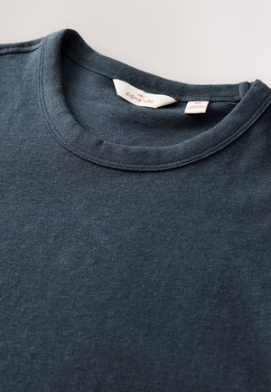 T-shirt bleu marine en coton, avec un col rond et une texture subtile. L'étiquette indique "Next Signature" avec des informations de taille.