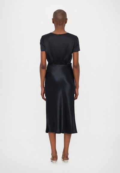 Črna satenasta obleka s kratkimi rokavi, gladko teksturo in sproščenim krojem. Se konča tik pod kolenom s subtilnim razširjenim robom.
