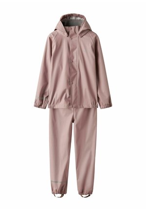 Veste imperméable rose avec capuche, boutons-pression et poignets élastiques, assortie à un pantalon avec des sangles de chevilles réglables.