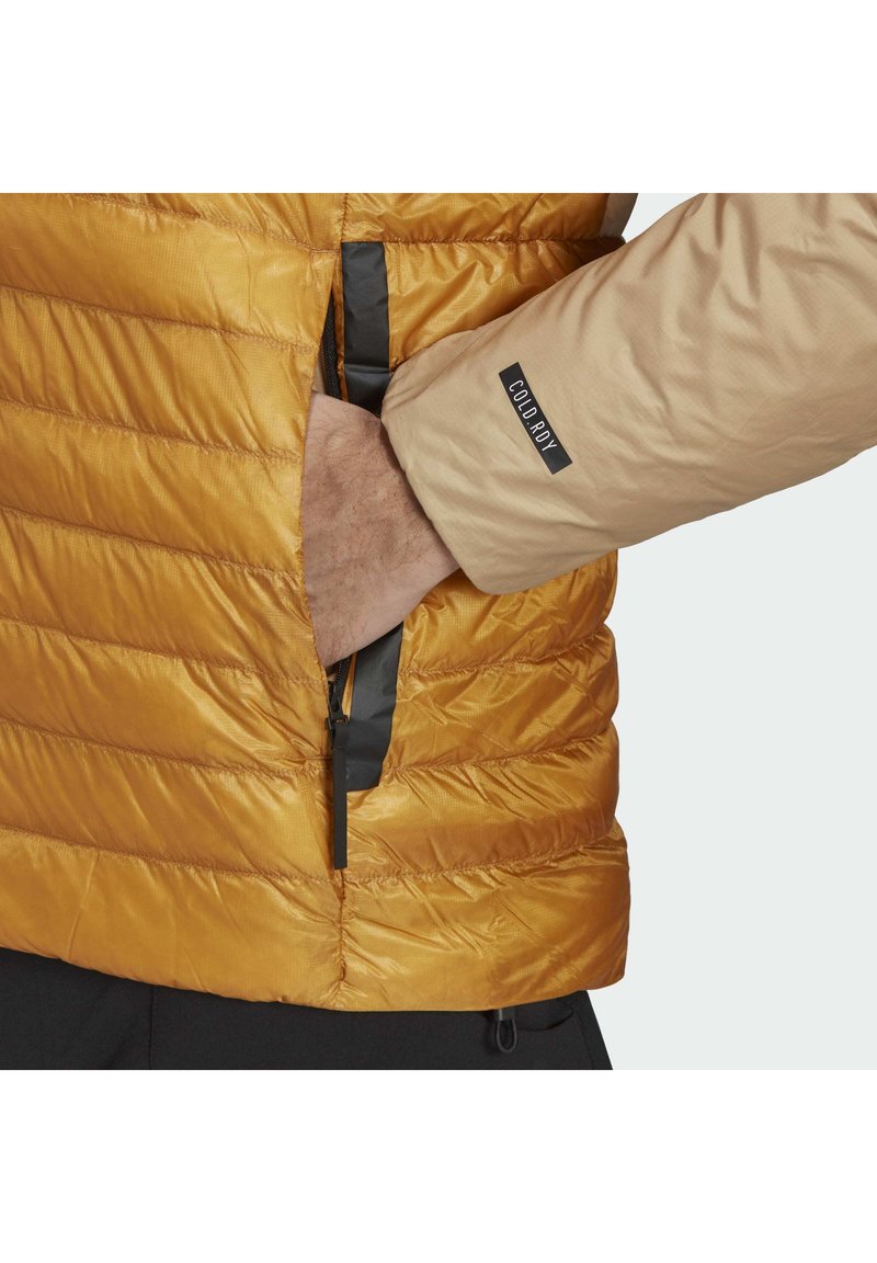 Wattierte Pufferjacke in goldbraun, mit horizontalen Nähten und einer Seitentasche mit einem schwarzen Reißverschluss, akzentuiert durch beigefarbenen Stoff.