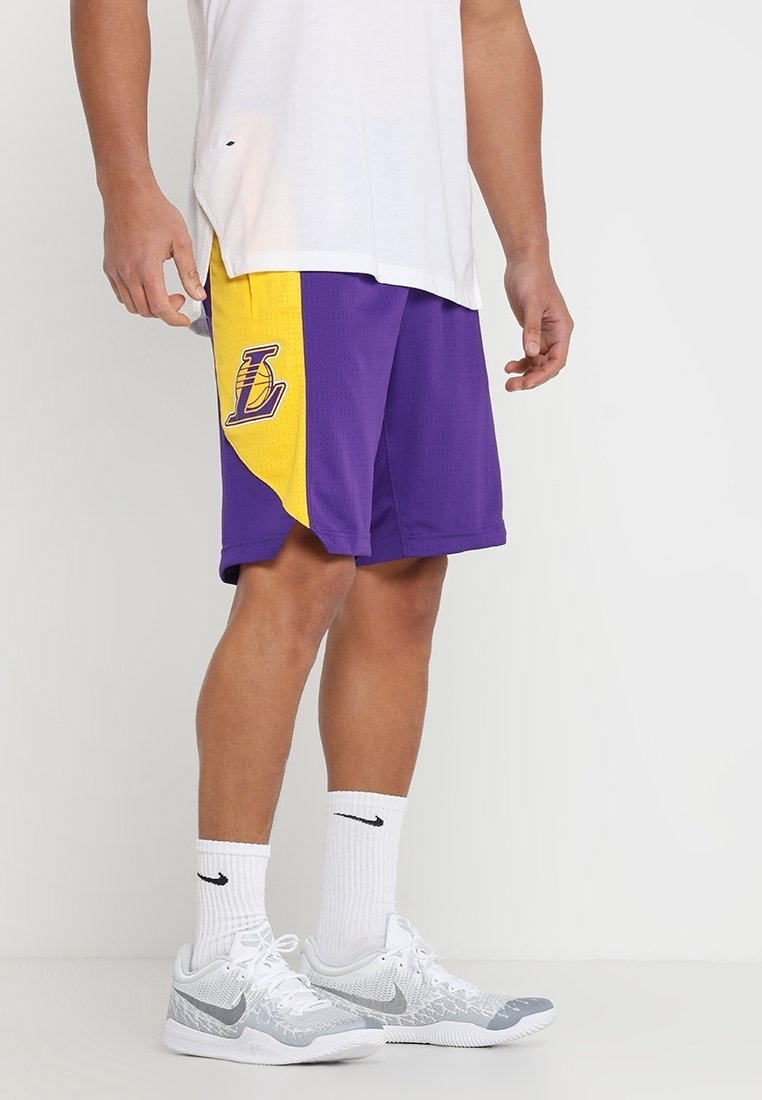 Violet ja keltased korvpallishortsid, millel on võrkpind ja vasakul küljel brodatsiooni logo. Kandmine koos valge särgi ja kingadega.