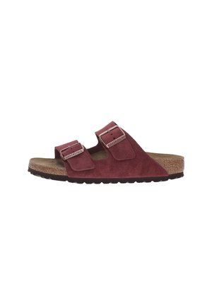 Le sandali in suede marroni presentano due cinghie regolabili con fibbie in metallo, una soletta in sughero e una suola in gomma testurizzata per migliorare la presa.