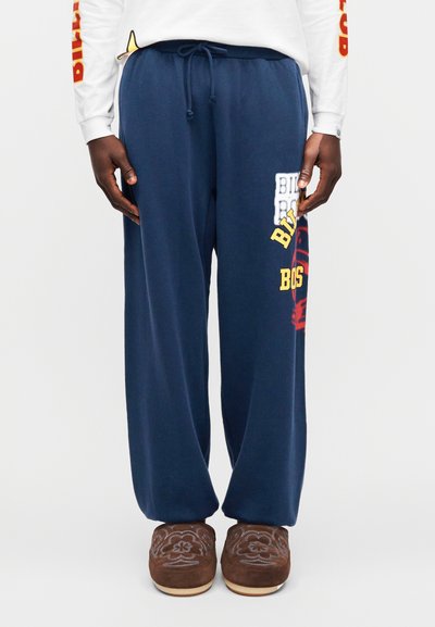 Σκούρα μπλε φούτερ από μαλακό ύφασμα με ελαστική μέση και κορδόνι. Διαθέτει τυπωμένο κείμενο σε κίτρινο και λευκό στην περιοχή του μηρού.