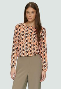 Langarmtop met een geometrisch patroon in oranje, bruin en beige. Gemaakt van een gladde stof met een ontspannen pasvorm en ronde halslijn.