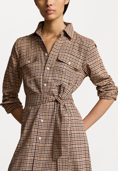 Καφέ και μπεζ καρό φόρεμα πουκάμισο από ύφασμα με δύο τσέπες στο στήθος και δεμένο μέση, διαθέτοντας μπροστινό κούμπωμα με κουμπιά και γυρισμένα μανίκια.