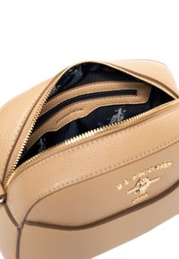 Borsa a mano in pelle color cammello con superficie texture, zip dorate e fodera in tessuto con motivo. Presenta scomparti interni e marchio.