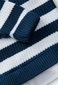 Blau-weißer gestreifter Strickstoff mit einer strukturierten Rippenoberfläche. Verfügt über einen kontrastierenden einfarbigen blauen Akzent am Rand. Weiches und atmungsaktives Material.