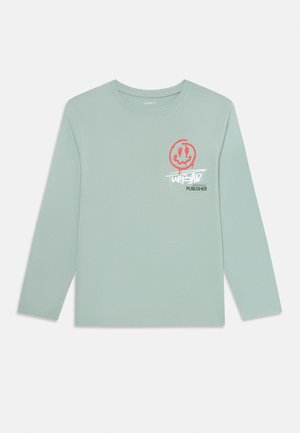 Hellgrünes Langarm-T-Shirt mit rotem, tropfendem Smiley-Gesicht-Graphic und weißem Graffiti-ähnlichem Text auf der linken Brust.
