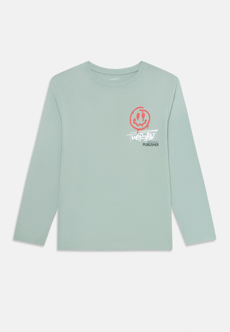 Hellgrünes Langarm-T-Shirt mit rotem, tropfendem Smiley-Gesicht-Graphic und weißem Graffiti-ähnlichem Text auf der linken Brust.