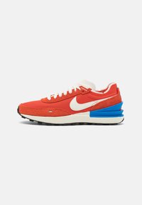 Red mesh and suede sneaker with cream laces, white swoosh, blue accents on the heel, and a textured black outsole.