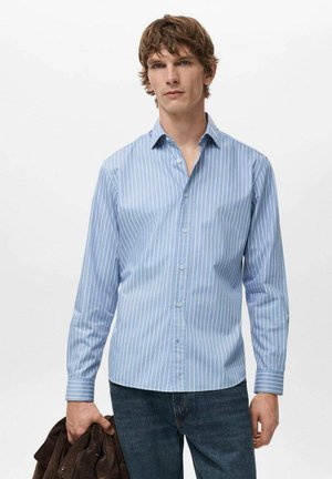 Blue button-up shirt with white vertical stripes, long sleeves, collar; material appears smooth; held jacket in the left hand; casual style.
