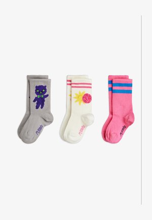 Drie paar kleurrijke kindersokken: grijs met paarse kat, wit met zon en roze bal, en roze met blauwe strepen.