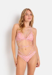 Bikini v roza in oranžnih prugah s trikotno zgornjim delom in križnimi trakovi na trupu in bokih, ki ima gladko teksturo tkanine.