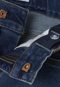 Denim džinsi ar tumšu mazgāšanu, kontrastējošām šuvēm, metāla pogu un elastīgu jostasvietu ar plastmasas pogas aizdari.