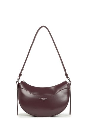 Petit sac à bandoulière en cuir marron foncé avec une forme courbée, une seule sangle, une fermeture éclair et le logo "Lancaster Paris" à l'avant.