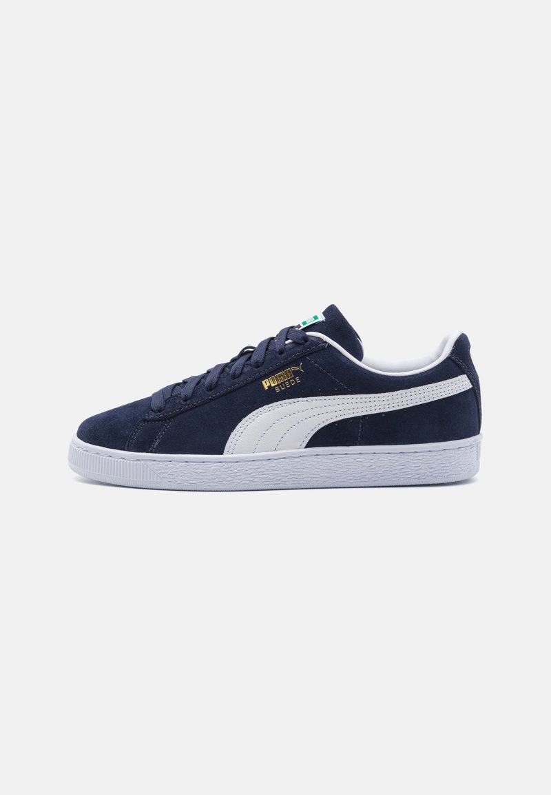 Baskets Puma en daim bleu marine avec bande blanche, semelle blanche, lacets blancs et logo Puma Suede doré sur le côté.