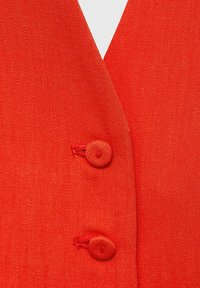 Red fabric with a textured finish, featuring two round buttons at the center, and a V-shaped neckline design.