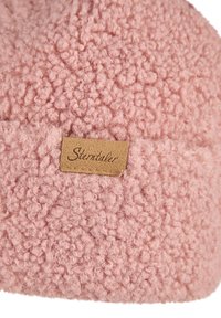 Pink curly textured fabric with a small rectangular tan label stitched on, displaying the word "Sterntaler" in cursive font.
