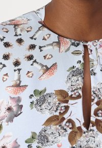 Himmelblauer Stoff mit einem floralen und woodland-Tierdruck, der Pilze, Igel und Blätter zeigt. Detail mit Schlüsselloch-Ausschnitt.