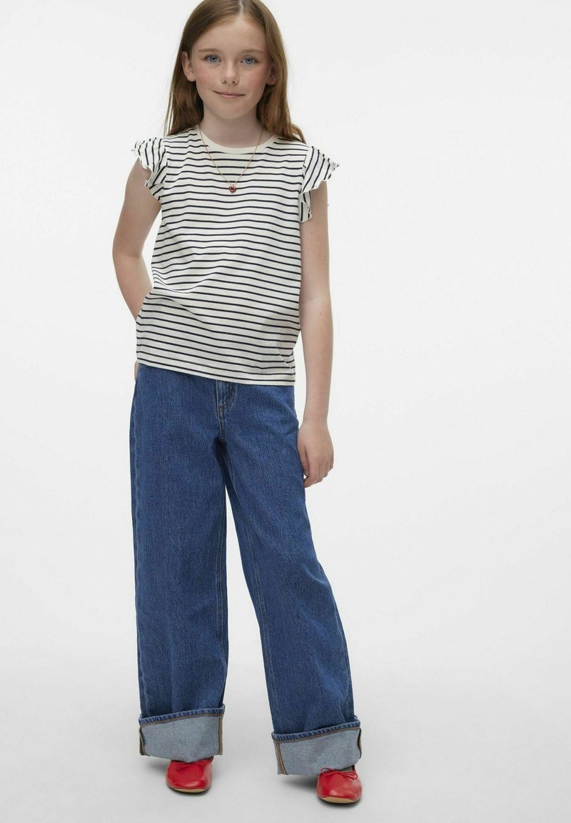 T-shirt di cotone a righe con maniche a volant, abbinato a jeans a gamba larga blu, con orli arrotolati e scarpe rosse per un look casual.