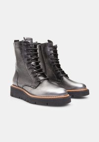 Bottines noires en cuir à lacets avec une finition texturée, bout arrondi et un fil blanc contrastant sur une semelle en caoutchouc épaisse.
