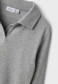 Helles graues Strickpolo mit strukturiertem Rippdesign, klassischem Kragen und einem dezenten Etikett im Nacken.