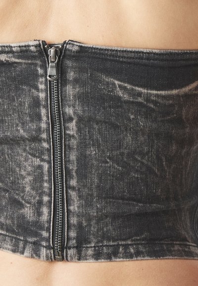 Black denim corset-style top with a front zipper, featuring a faded texture and a structured fit, highlighting a smooth edge at the hem.