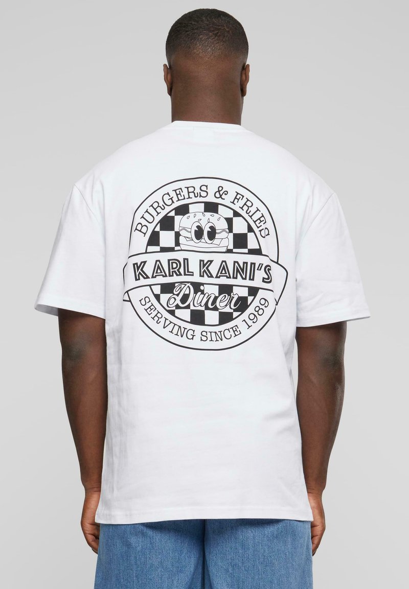 Biely bavlnený tričko s čiernym grafickým potlačou loga jedálne, s kockovanými akcentmi a textom: "BURGER & FRIES," "KARL KANI’S DINER."