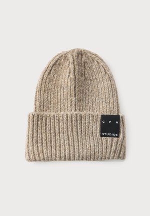 Gorro beige de punto acanalado con ala doblada y una etiqueta rectangular negra con la inscripción "CPH STUDIOS" en el puño.