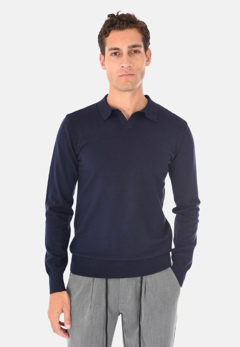 Maglione in lana blu navy con scollo a V e colletto corto, dotato di maniche lunghe e vita aderente. Tessuto liscio, dettagli minimi.