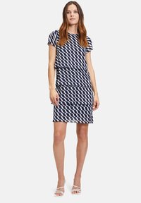 Marineblaues Kleid mit einem wellenförmigen weißen Muster, das kurze Ärmel und ein tailliertes Design hat, das oberhalb des Knies endet. Glatte Stoffstruktur.