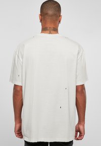 Grå oversized T-skjorte med rund hals, med ripede detaljer og en avslappet passform. Stoffet virker mykt med en lett tekstur.