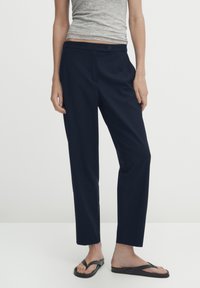 Navy blue, tailored pants with a straight leg, featuring a button closure and front pockets. Made from a smooth fabric, designed for comfort.