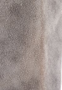 Gros plan de cuir suédé gris montrant sa surface douce, texturée, légèrement duveteuse avec de fines fibres et de légères variations de teinte.