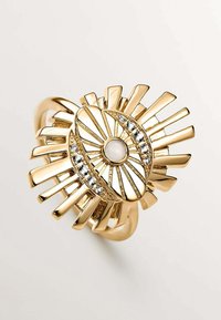 Anillo de oro con una perla blanca central y acentos de cristal, con un diseño de erupción solar de rayos alargados que se extienden desde el centro.