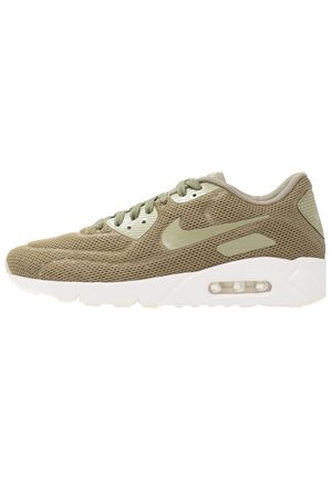 Lyse olivengrøn mesh Nike sneaker med matchende snørebånd, beige logo og hvid sål med synlig luftpude i siden.